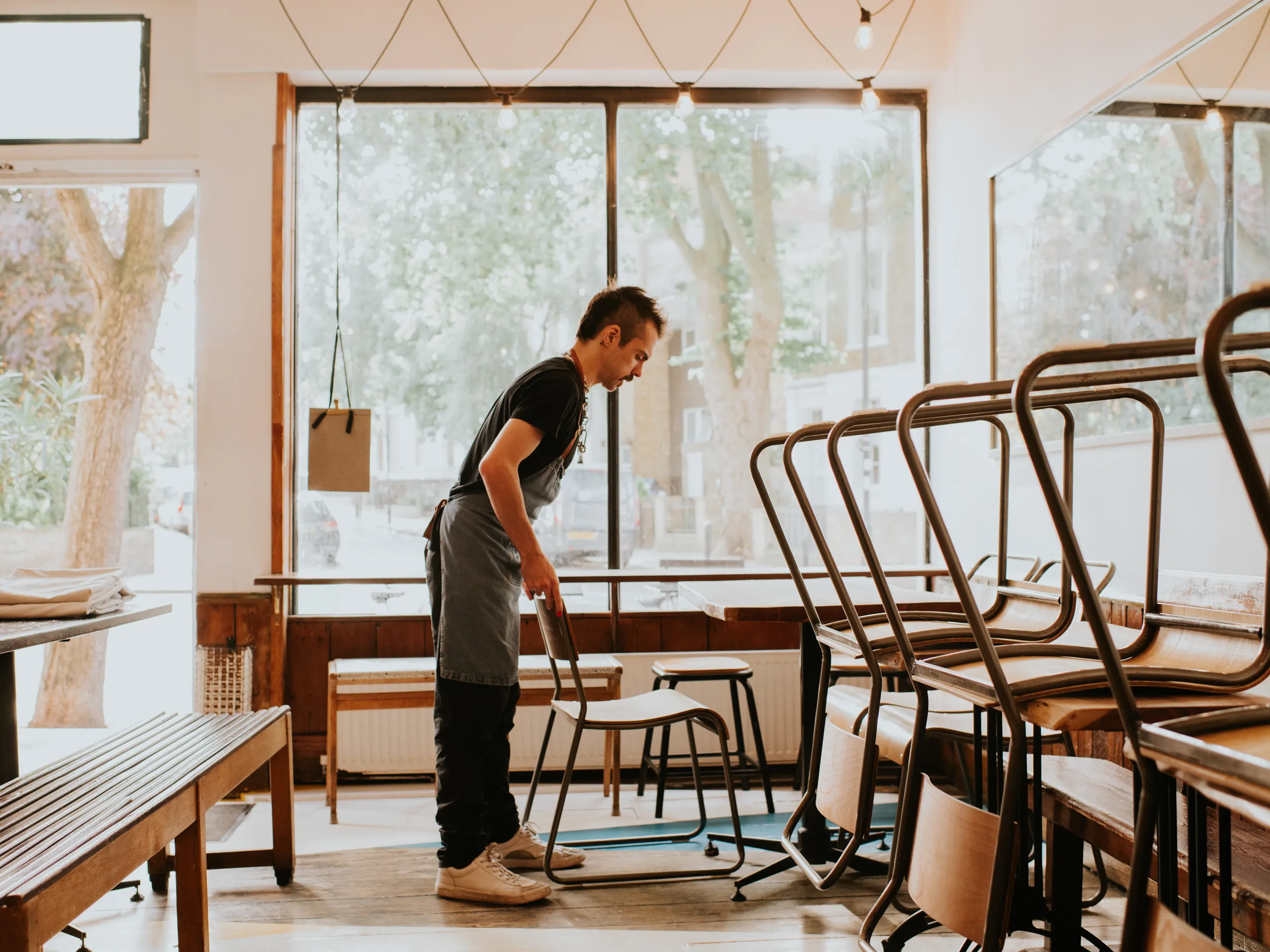 Inhaber räumt Stühle im Café auf